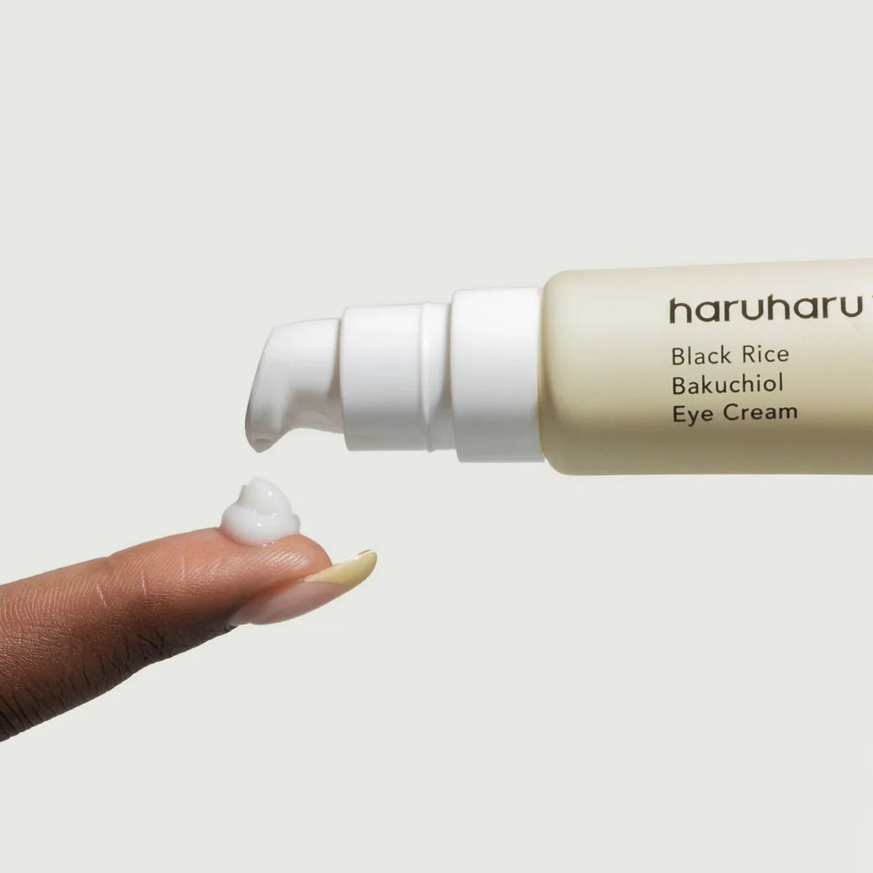 Haruharu Black Rice Bakuchiol Eye Cream with a hand applying cream on a light background