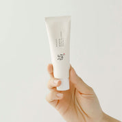 Hand holding a Beauty of Joseon Relief Sun Rice + Probiotics SPF50+ tube against a light gray background