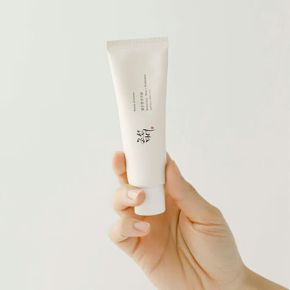 Hand holding a Beauty of Joseon Relief Sun Rice + Probiotics SPF50+ tube against a light gray background