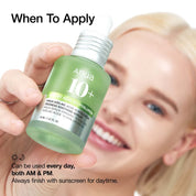 Hand holding a green skincare bottle with text about application times, against a blurred background of a smiling person.