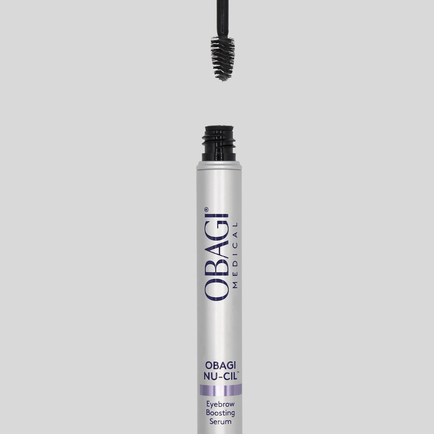 Obagi Nu-Cil eyebrow serum with applicator on a gray background
