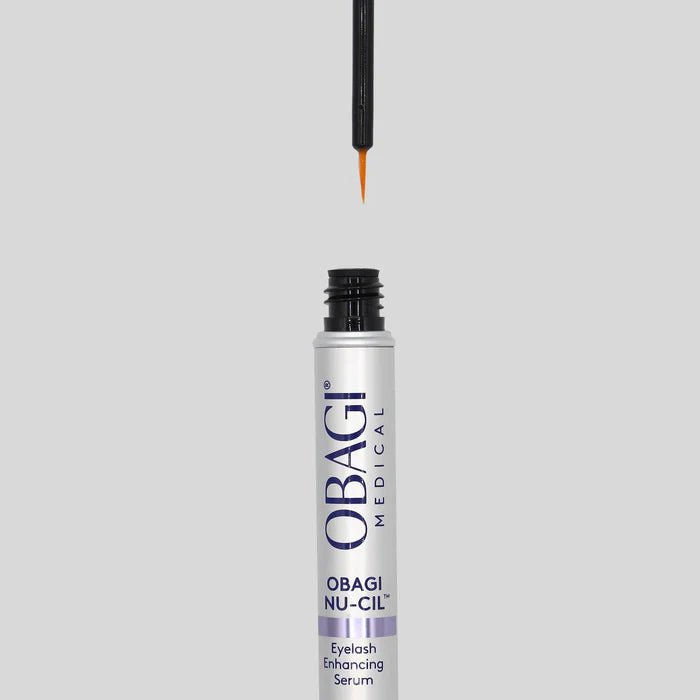 Obagi Nu-Gil eyelash enhancing serum bottle with applicator on a gray background