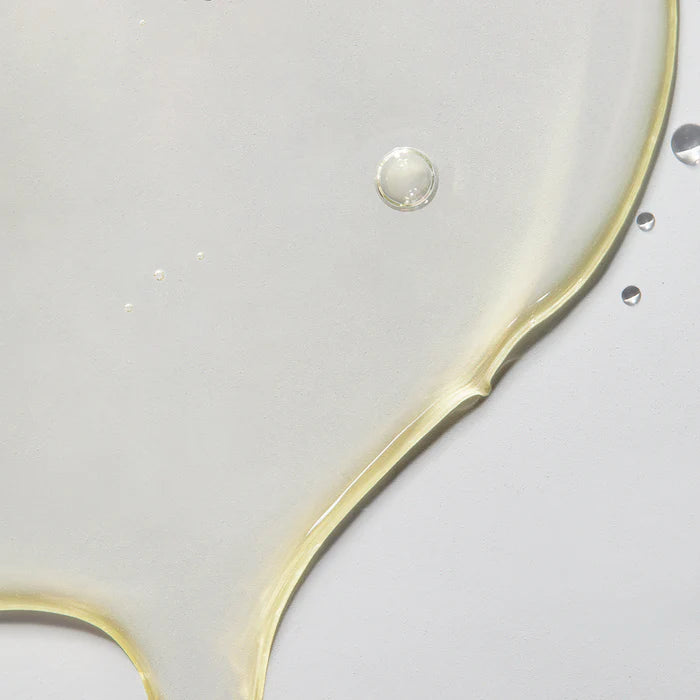 Close-up of a gold ring with a clear gemstone on a light gray background