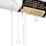 Cosmetic bottle with droplets of product on a white background