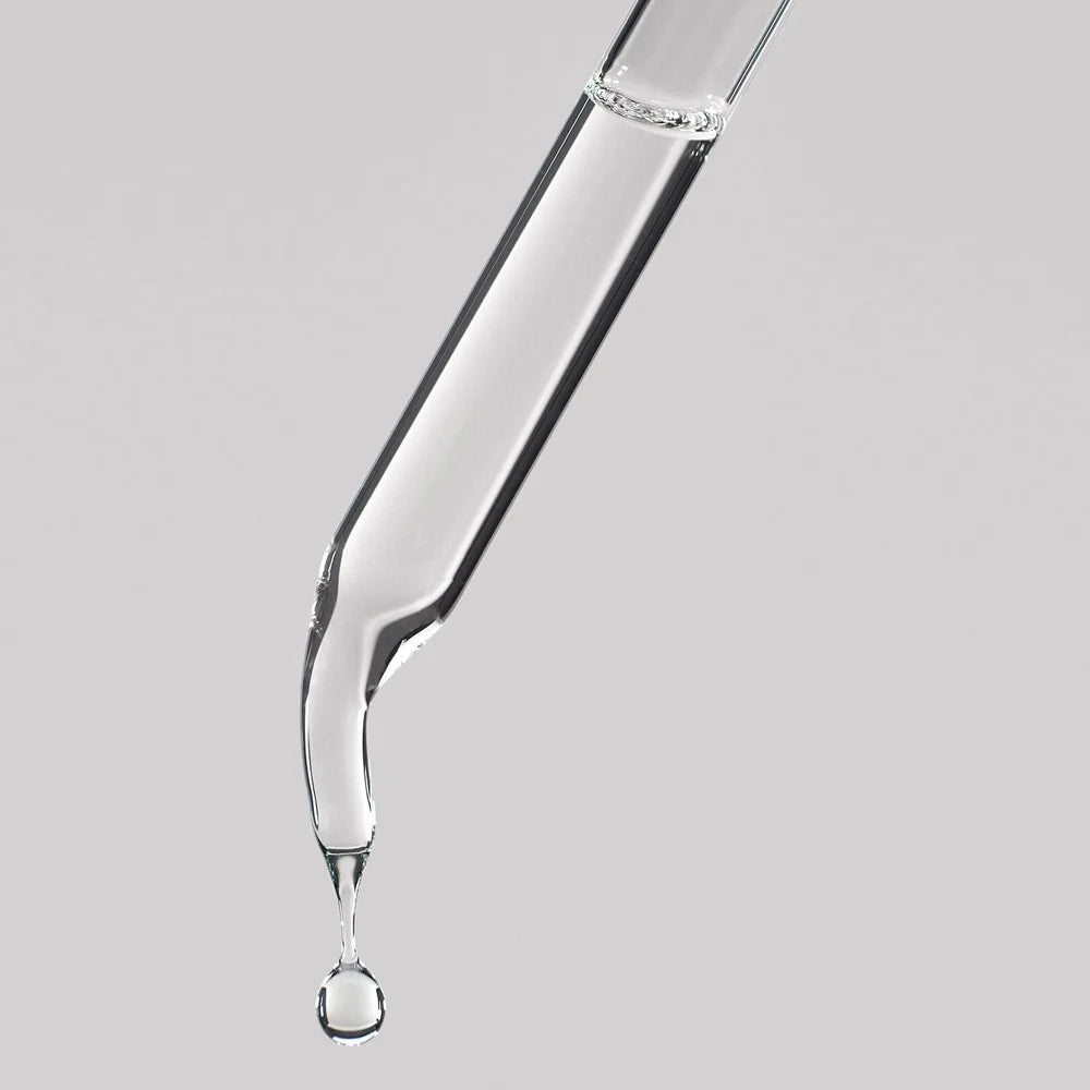 Glass dropper with clear liquid on a gray background